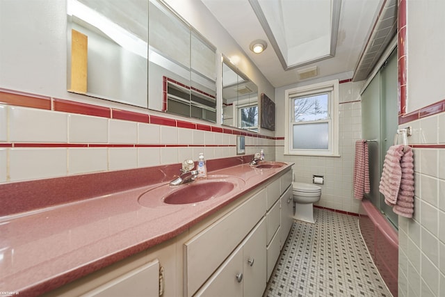 bathroom featuring vanity, toilet, and tile walls