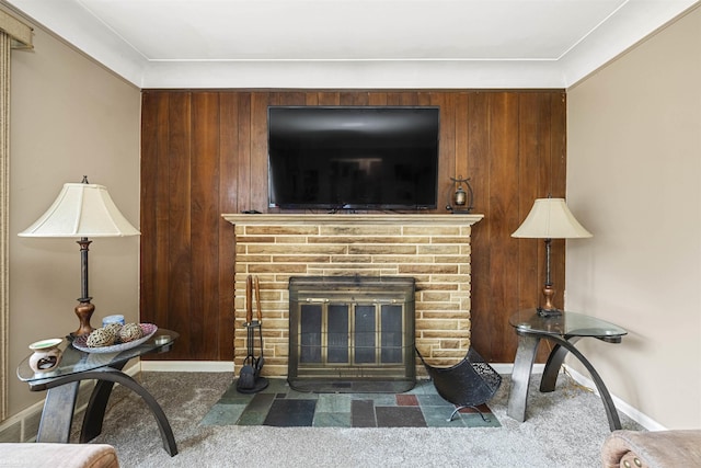 living room featuring a fireplace, carpet, crown molding, and wooden walls