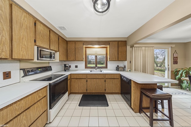 kitchen featuring stainless steel microwave, a kitchen breakfast bar, black dishwasher, white electric range oven, and kitchen peninsula