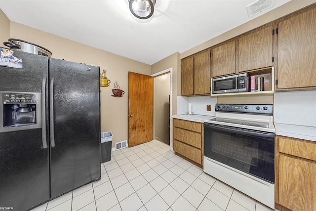 kitchen featuring white electric range oven, light tile patterned floors, and black refrigerator with ice dispenser