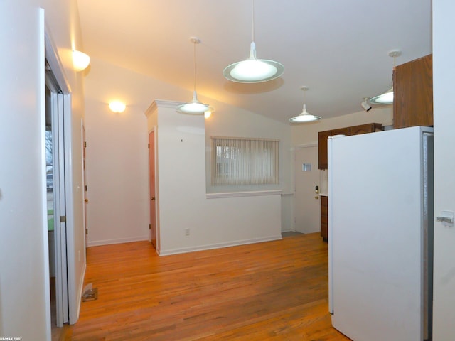 kitchen featuring pendant lighting, white refrigerator, lofted ceiling, and light hardwood / wood-style flooring