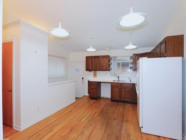 kitchen featuring pendant lighting, white refrigerator, light wood-type flooring, and sink