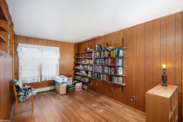 living area featuring hardwood / wood-style floors, baseboard heating, and wooden walls