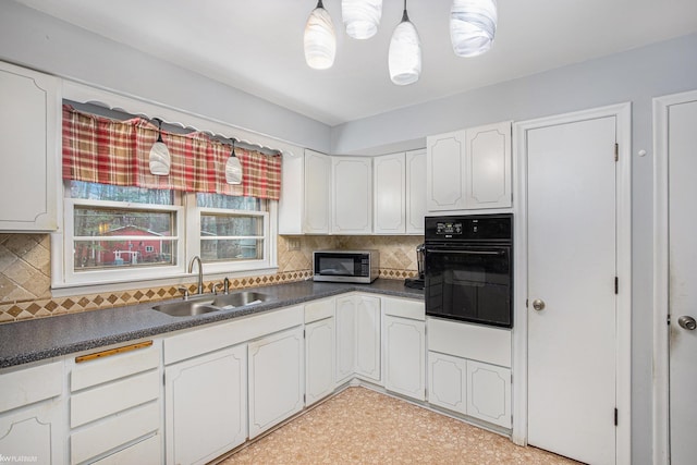 kitchen featuring sink, backsplash, oven, pendant lighting, and white cabinets