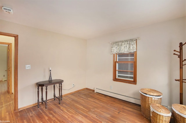 unfurnished room with a baseboard radiator and hardwood / wood-style flooring