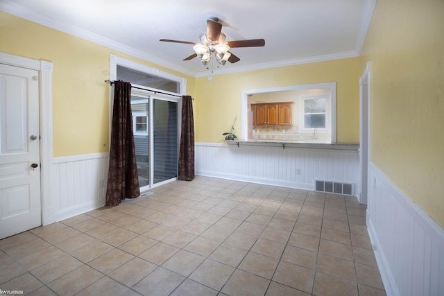 tiled spare room featuring crown molding and ceiling fan