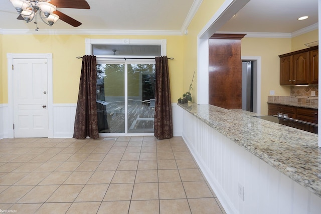 kitchen featuring light stone counters, ceiling fan, ornamental molding, and light tile patterned floors