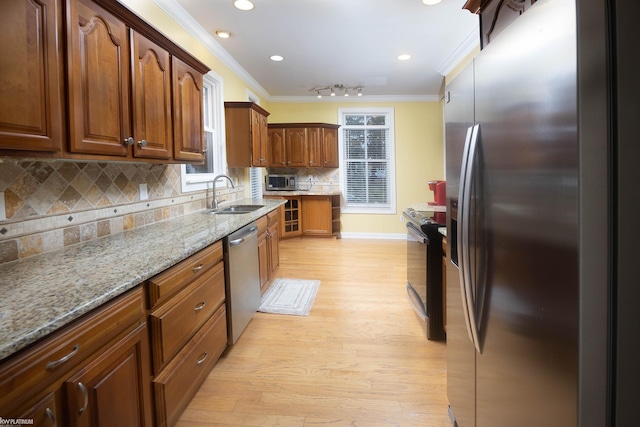 kitchen featuring appliances with stainless steel finishes, sink, backsplash, light stone counters, and crown molding