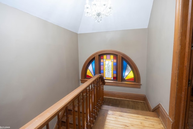 stairway featuring lofted ceiling, hardwood / wood-style floors, and a chandelier