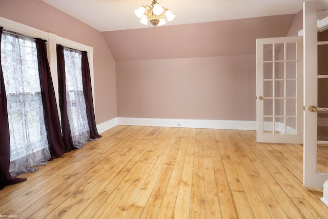 additional living space with lofted ceiling, light hardwood / wood-style flooring, and a chandelier