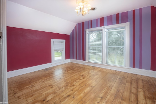 additional living space with vaulted ceiling, wood-type flooring, and an inviting chandelier