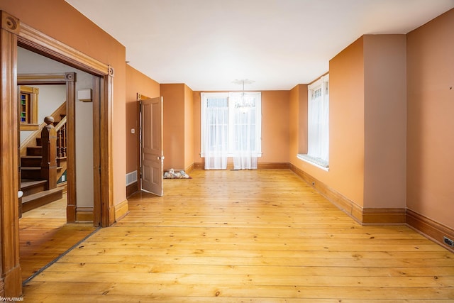 unfurnished room featuring a chandelier and light wood-type flooring