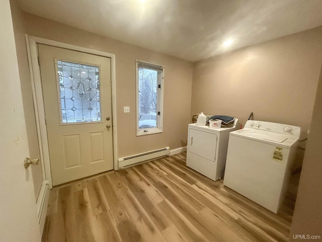 washroom with washing machine and dryer, baseboard heating, and light hardwood / wood-style flooring