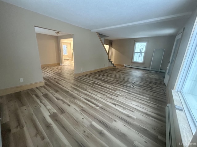 301 E Chocolay St, Munising, MI 49862 - unfurnished living room with a baseboard radiator, stairs, and wood finished floors