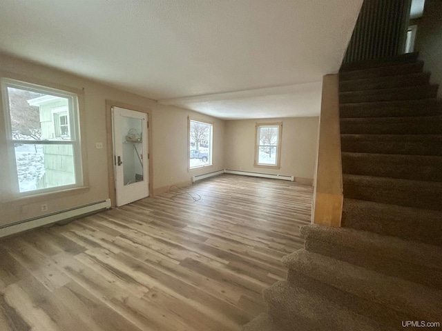 unfurnished living room with a baseboard heating unit and light hardwood / wood-style flooring