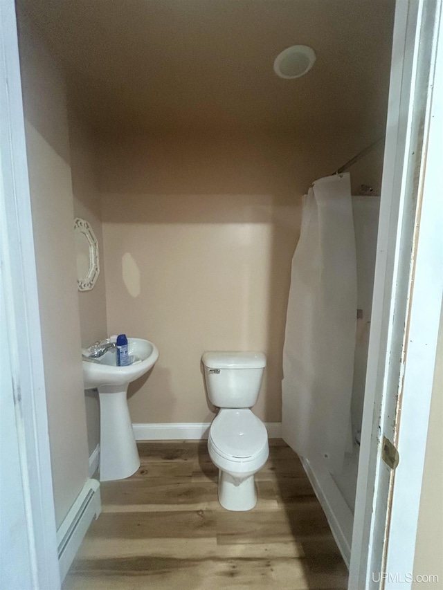 bathroom with toilet, hardwood / wood-style floors, and a baseboard heating unit