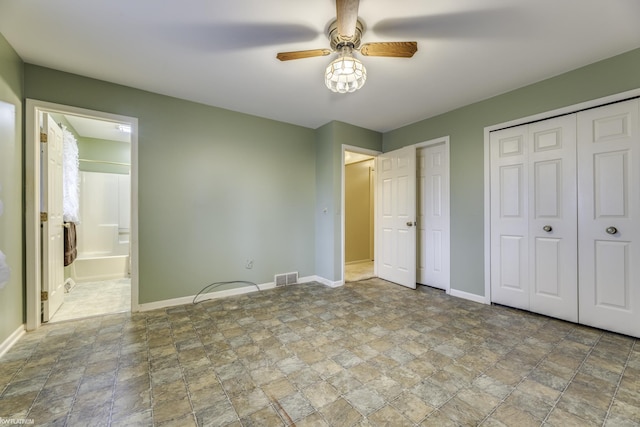 unfurnished bedroom with ensuite bath, ceiling fan, and two closets