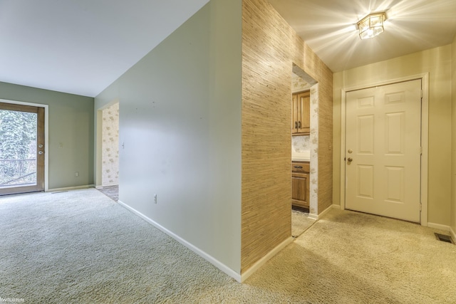 hallway featuring light colored carpet and vaulted ceiling