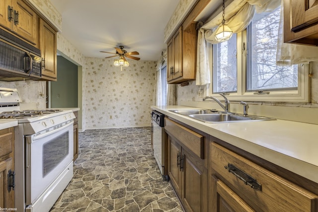 kitchen featuring ceiling fan, sink, hanging light fixtures, and white appliances