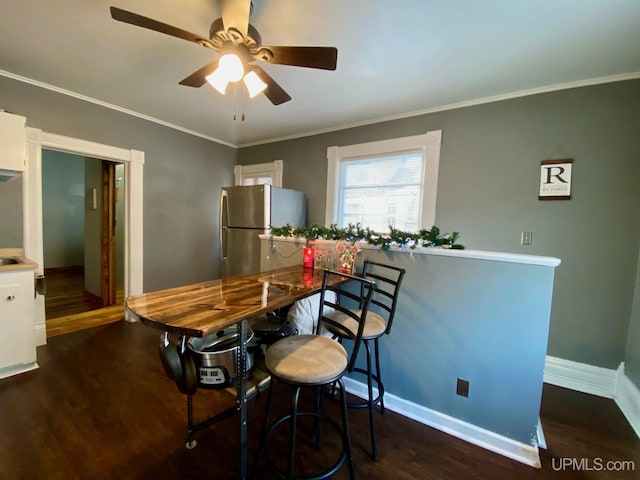 dining room with dark wood-type flooring, ornamental molding, and ceiling fan