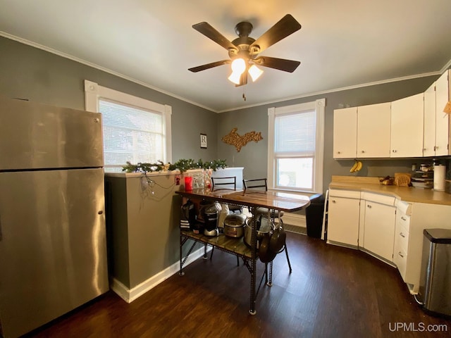 kitchen with white cabinets, stainless steel fridge, dark hardwood / wood-style floors, ornamental molding, and ceiling fan