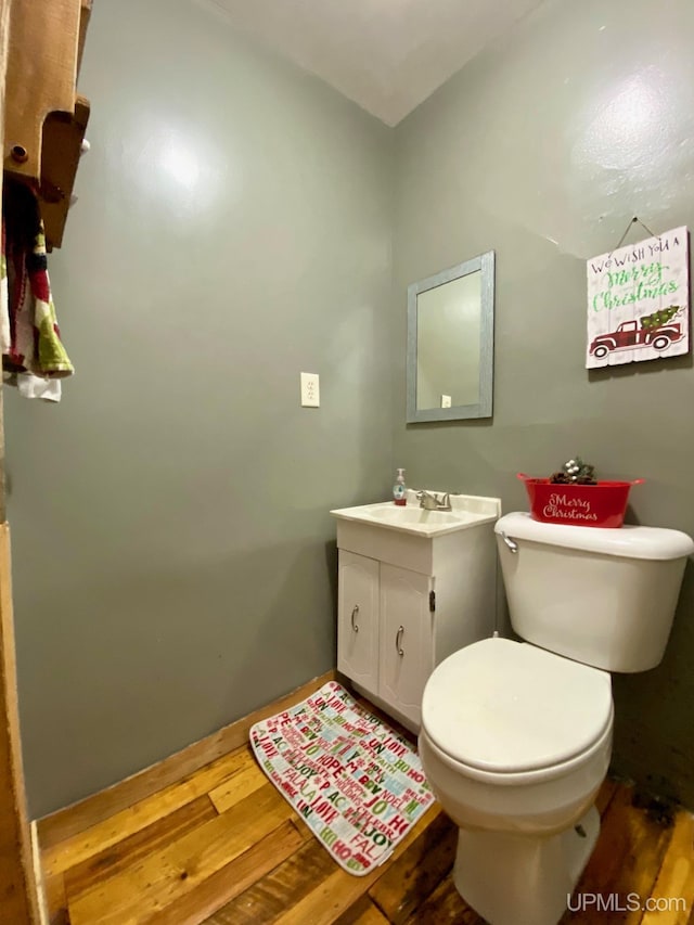 bathroom with toilet, vanity, and hardwood / wood-style floors