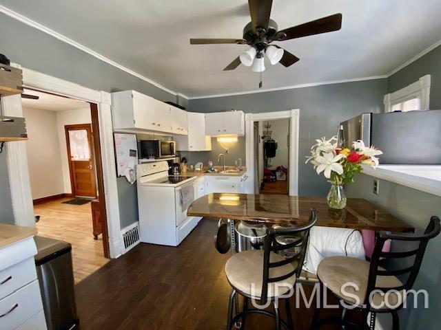 kitchen with ceiling fan, stainless steel appliances, wood-type flooring, white cabinets, and sink