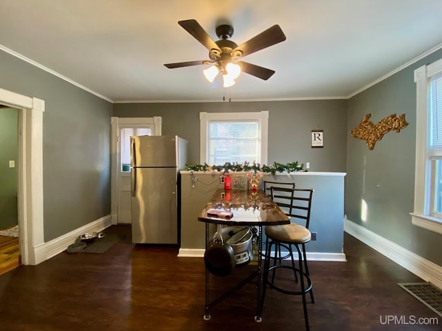 dining room with dark wood-type flooring, ceiling fan, and crown molding