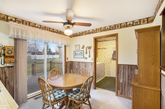 dining space featuring washer / clothes dryer, wooden walls, ceiling fan, and light colored carpet