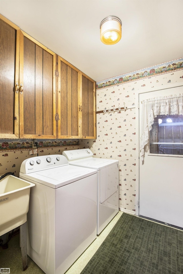 clothes washing area featuring washing machine and dryer, sink, and cabinets