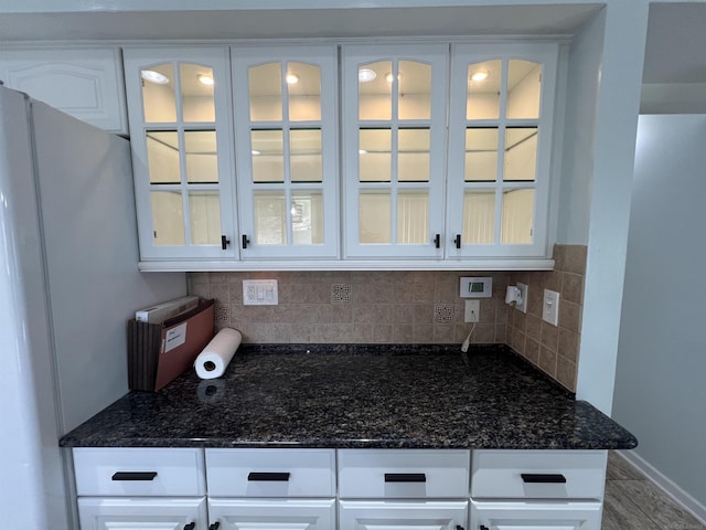 room details featuring dark stone countertops, white cabinetry, and backsplash