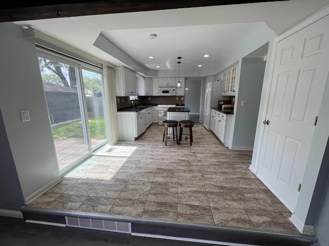 kitchen with a center island, white appliances, tasteful backsplash, decorative light fixtures, and a breakfast bar area