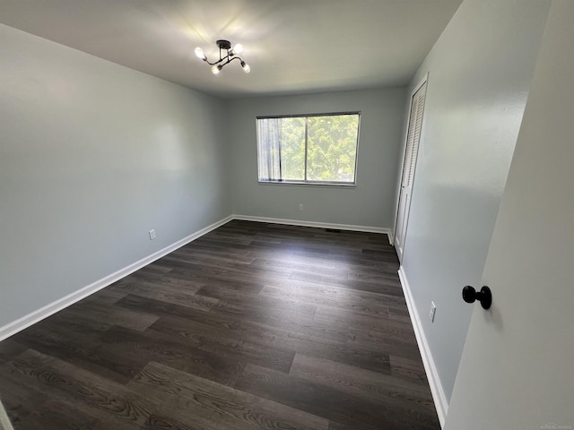 unfurnished room with a chandelier and dark hardwood / wood-style floors