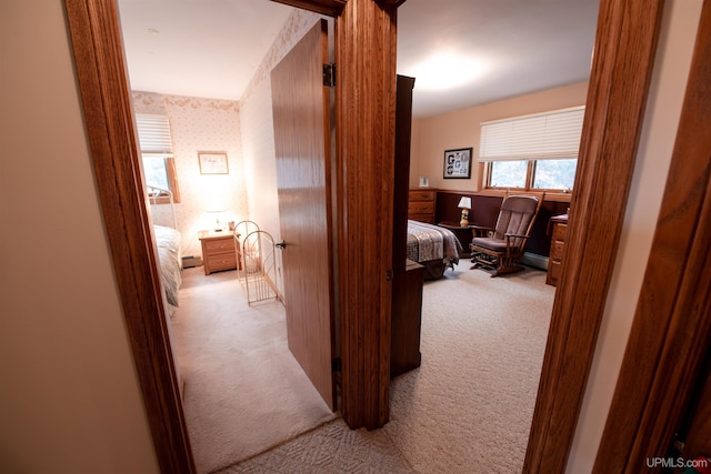 hall with light colored carpet and a baseboard heating unit