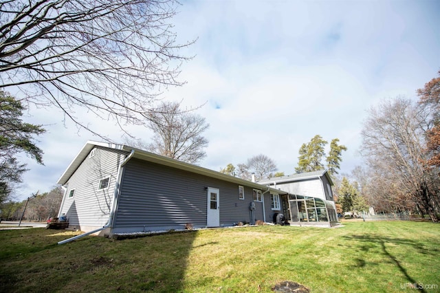 back of property with a lawn and a sunroom