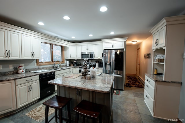 kitchen with light stone countertops, appliances with stainless steel finishes, a center island, and white cabinetry