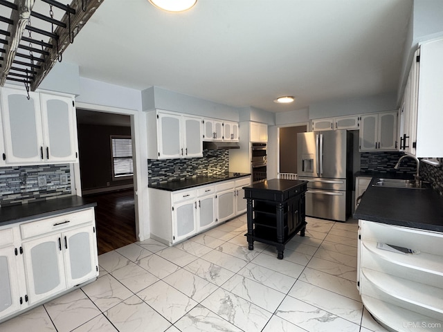 kitchen featuring backsplash, white cabinets, sink, a kitchen island, and stainless steel appliances