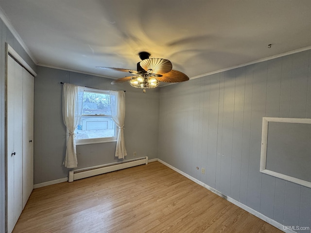 interior space with ceiling fan, light hardwood / wood-style flooring, a baseboard heating unit, wood walls, and ornamental molding