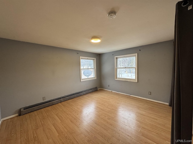 empty room featuring light wood-type flooring and a baseboard heating unit