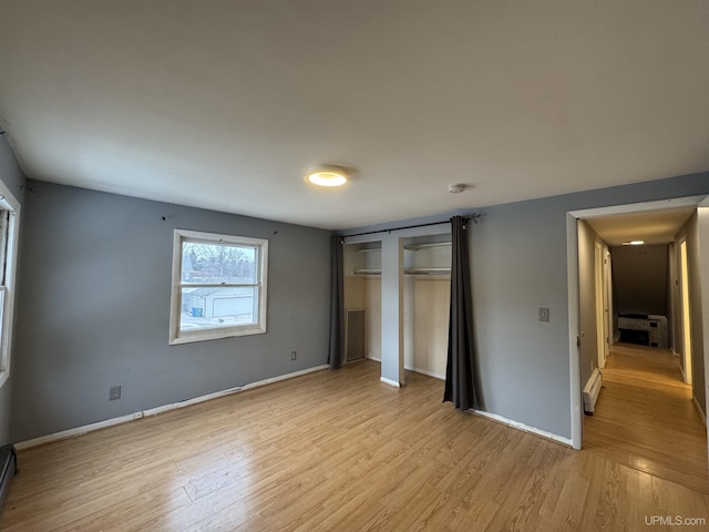 unfurnished bedroom featuring light hardwood / wood-style flooring and a baseboard radiator