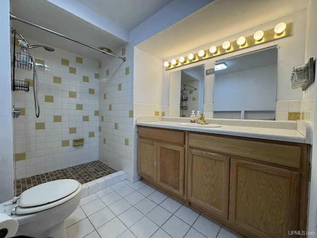 bathroom with vanity, tiled shower, tile walls, tile patterned flooring, and toilet