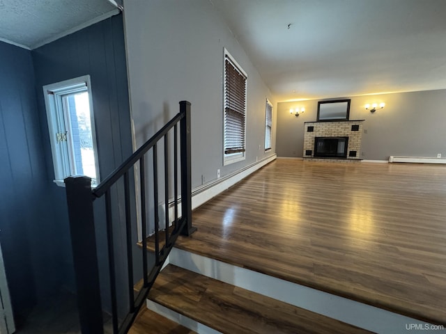 unfurnished living room with a fireplace, hardwood / wood-style flooring, baseboard heating, and ornamental molding