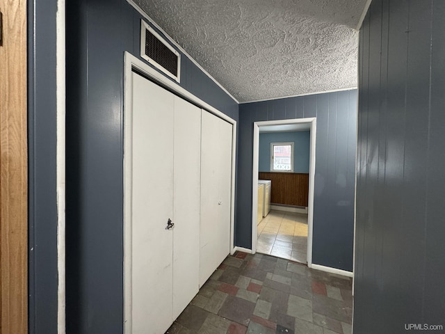 hall featuring ornamental molding, a textured ceiling, wooden walls, and a baseboard radiator