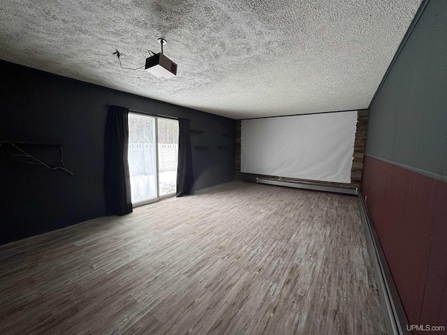 empty room with wood-type flooring, a textured ceiling, and baseboard heating