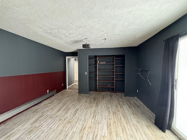 interior space featuring hardwood / wood-style floors, baseboard heating, and a textured ceiling