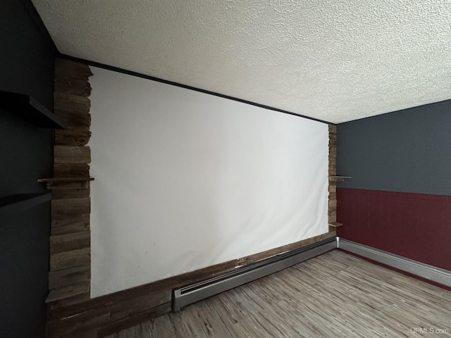 interior space with wood-type flooring, a textured ceiling, and a baseboard heating unit