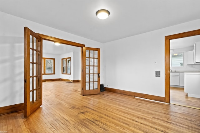 empty room featuring french doors and light hardwood / wood-style flooring