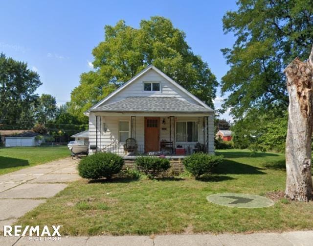 bungalow with covered porch and a front lawn