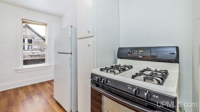 kitchen featuring white cabinets, light hardwood / wood-style floors, and white appliances