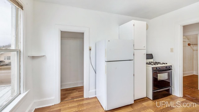 kitchen featuring plenty of natural light, white fridge, range with gas stovetop, and light wood-type flooring